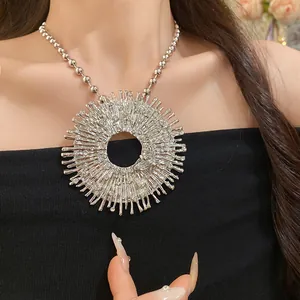 Close-up of silver textured sunburst pendant necklace with a small rhinestone bee detail.