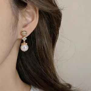 Detailed view of an elegant gold-plated clover pearl earring worn on a model's ear