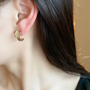 Close-up of model wearing 18k gold plated C-shape earrings with quilted texture