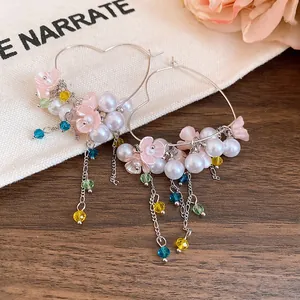Close-up detail of heart hoop earrings featuring pink resin flowers and white pearls
