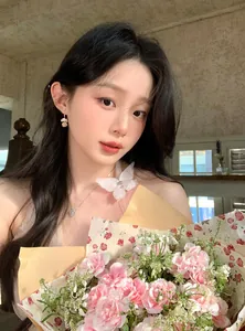 Detailed view of elegant pearl flower ball earrings worn by a model with a flower bouquet