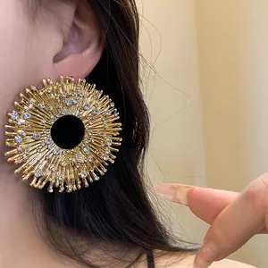 Detailed close-up of a vintage gold sunburst earring with rhinestones and a bee motif.