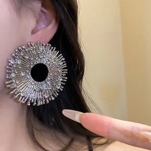 Detailed view of oversized sunburst silver earrings with rhinestone accents