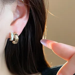 Detailed view of quilted 18k gold plated C-shaped earring with white inlay on ear