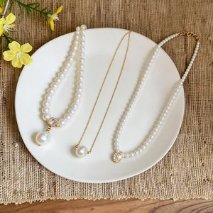 Detail shot of three elegant pearl necklaces with gold plating on a white plate.