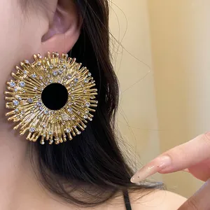 Detailed view of a large gold sunburst earring featuring a sparkling diamond bee motif