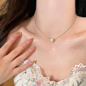Close-up detail view of an elegant 14k gold plated pearl necklace on a model collarbone