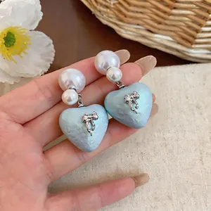 Light blue heart dangling earrings with pearl studs and silver bow detail for women