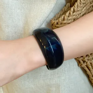Primo piano dettagliato del bracciale rigido geometrico in acrilico blu scuro al polso