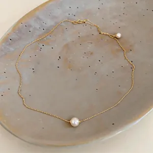 Close-up of a 14k gold plated necklace with a minimalist pearl pendant