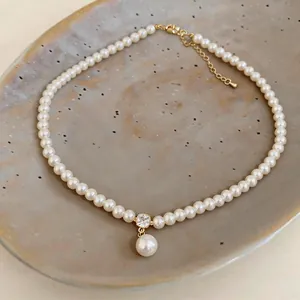 Macro view of a 14k gold plated pearl necklace with a crystal and drop pearl pendant