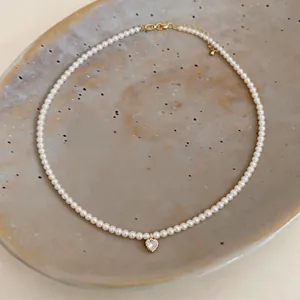 Detailed view of elegant 14k gold plated pearl necklace featuring a sparkling heart pendant.