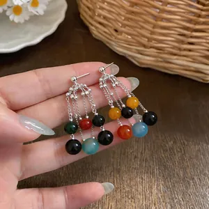 Dettaglio degli orecchini con nappe in perle d'agata multicolore e ago d'argento