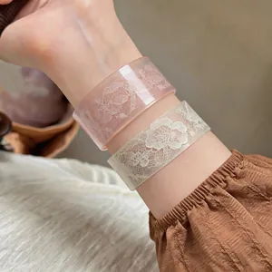 Close-up shot of elegant pink and white acrylic bangles with lace floral print designs