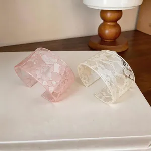 Close-up of pink and cream acrylic cuff bracelets with delicate lace floral patterns