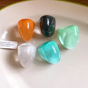 Detailed macro view showing five colorful chunky resin rings with marbled textures on a white plate