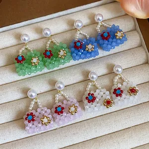 Close-up of colorful beaded handbag earrings with pearl studs on beige jewelry tray