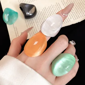 Detailed close-up view of colorful irregular resin rings with pearly shimmer worn on hand