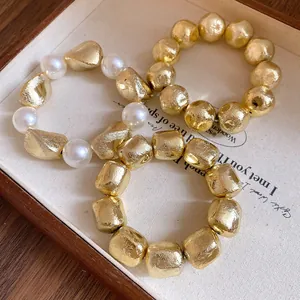 Detailed macro view of gold foil textured geometric beads and elegant white pearls