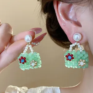 Detail view of dopamine beaded bag earrings with pearls and floral accents