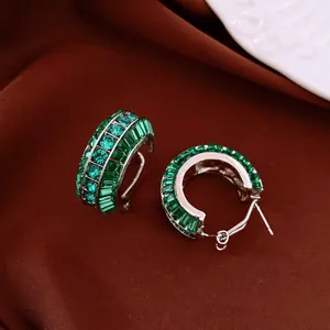 Primo piano di orecchini a cerchio vintage con cristalli verde smeraldo e ago argento.