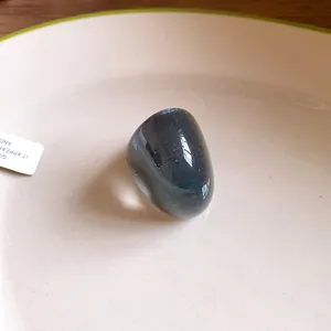 Close-up of an oversized irregular translucent grey resin wide ring on a white plate