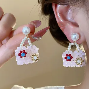 Close-up of cute dopamine bag-shaped pearl earrings with colorful floral bead details.