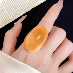 Close-up detail of a chunky orange resin ring with a unique irregular design on a hand