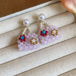 Close-up of pink beaded handbag earrings with floral accents and white pearls