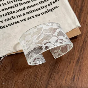 Detail view of a translucent acrylic cuff bracelet with delicate white lace print