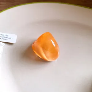 Macro detail of a translucent orange resin ring with an irregular wide band design