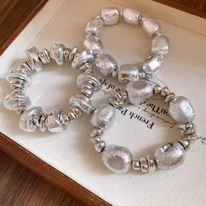 Close-up view of three vintage silver irregular geometric beaded bracelets on a fabric tray