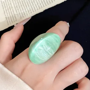 Macro view showing the glossy texture of a light green irregular resin wide band ring