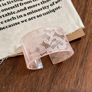 Close-up of pink acrylic cuff bracelet featuring delicate white lace floral pattern details