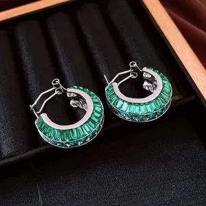 Vista dettagliata di eleganti orecchini a cerchio in argento con pietre baguette verde smeraldo
