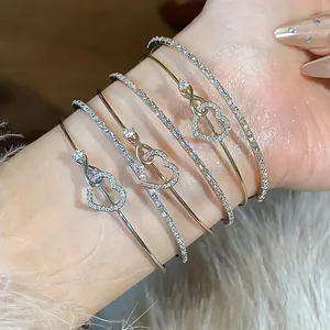 Primer plano de elegantes pulseras en capas de oro rosa y plata con motivos de corazón