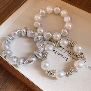 Close-up of retro irregular silver and pearl beaded bracelets on a vintage tray.