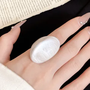 Detailed view of an exaggerated irregular white resin ring featuring a pearlescent finish