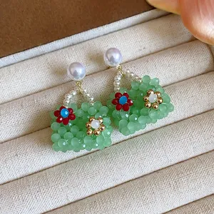 Detailed shot of green beaded handbag earrings with pearl studs and flower accents