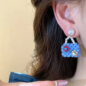 Close-up detail of a charming blue beaded handbag earring with a pearl stud decoration.