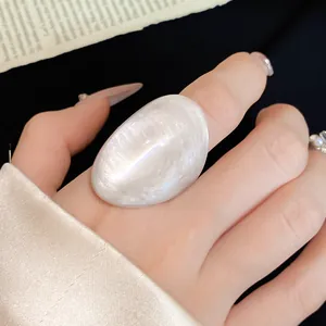 Close-up detail of a unique irregular pearlescent white resin wide band fashion ring