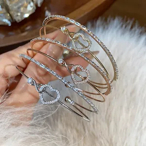 Primer plano de elegantes brazaletes de doble capa con corazones y circonitas en oro rosa.