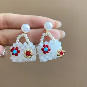 Close-up of handmade handbag-shaped pearl earrings with colorful bead accents