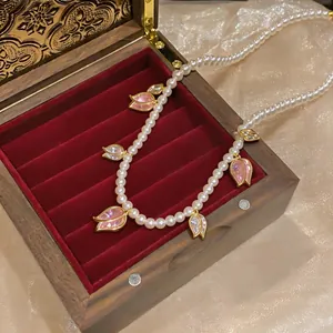Détail d'un collier de perles avec des breloques tulipes en zircone rose en boîte