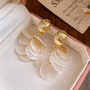 Macro detail view of 14k gold plated tassel earrings with layered white shell rounds