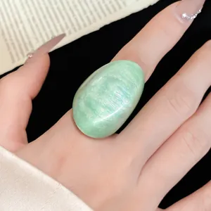 Close-up of a large irregular mint green resin ring with a shimmering cat-eye effect