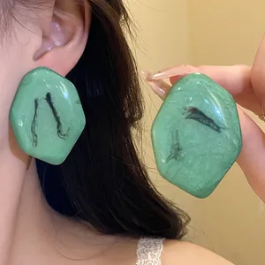 Primo piano di orecchini vintage in resina verde con motivo marmorizzato su un modello