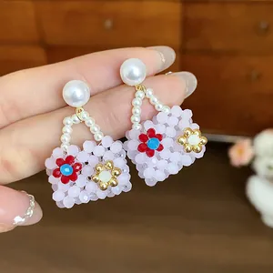 Detailed macro view of sweet bag-shaped beaded earrings with pearls and floral accents.