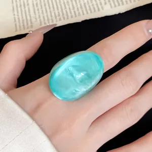 Close-up of irregular turquoise resin ring on finger with unique translucent finish