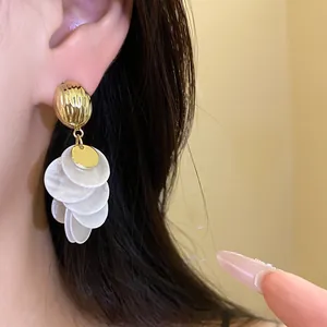Detailed close-up of 14k gold plated earrings featuring cascading white shell round discs